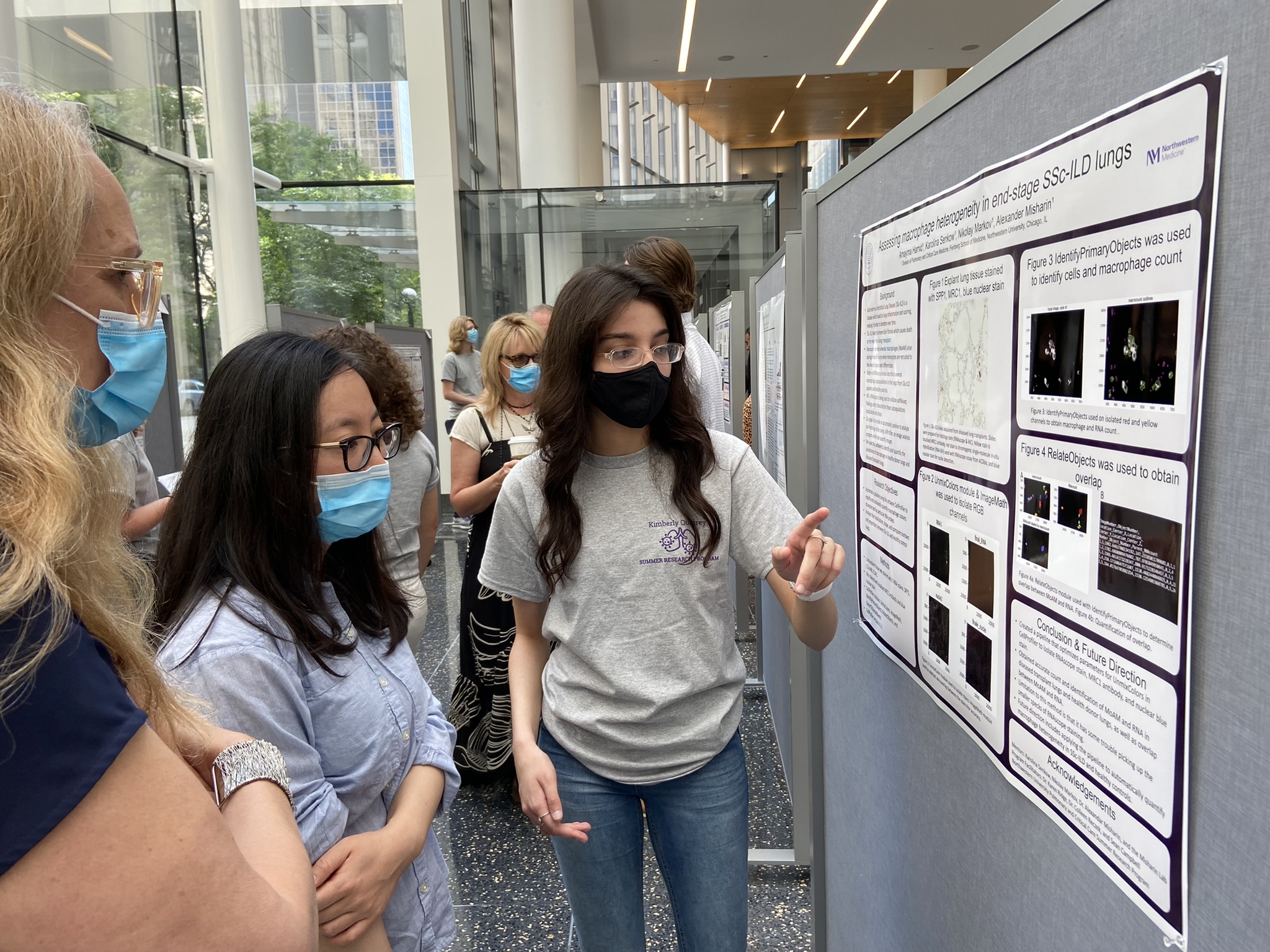 An intern points to her poster while presenting at the Kimberly Querrey Research Symposium